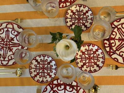 Vajilla con platos en porcelana blanca con rejas rojas y cubertería.